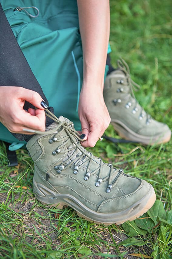 Donna allaccia stivali da trekking