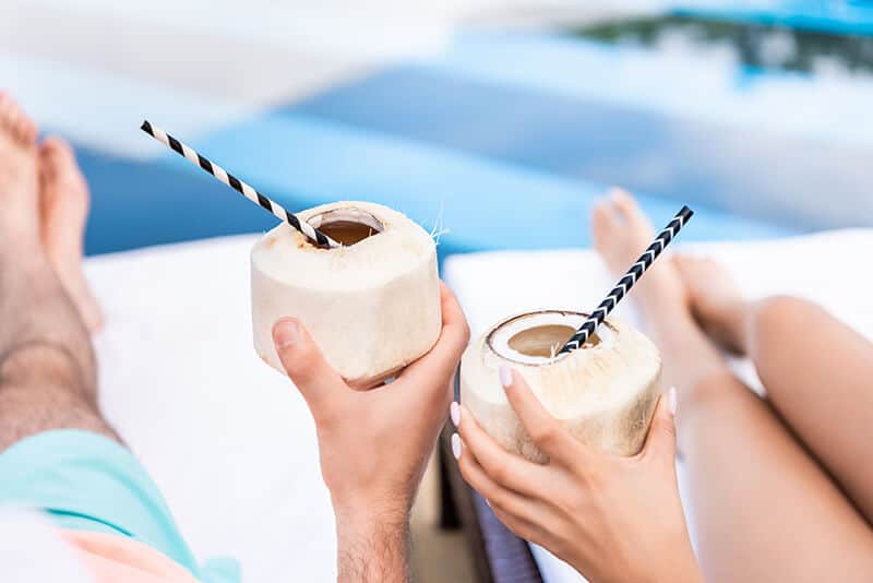 Couple sipping coconut drinks by the pool