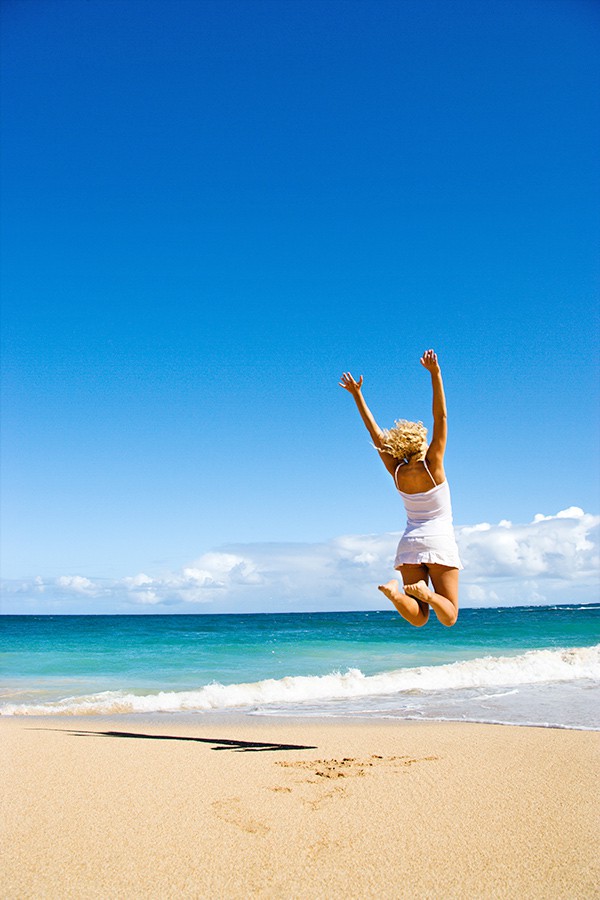 Woman jumping on a beach in Oahu