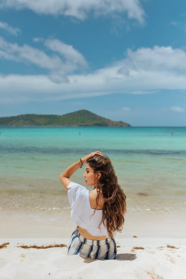Woman sitting on a white sand beach in Oahu