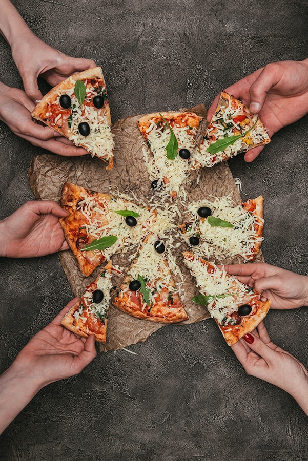 Hands grabbing a large pizza