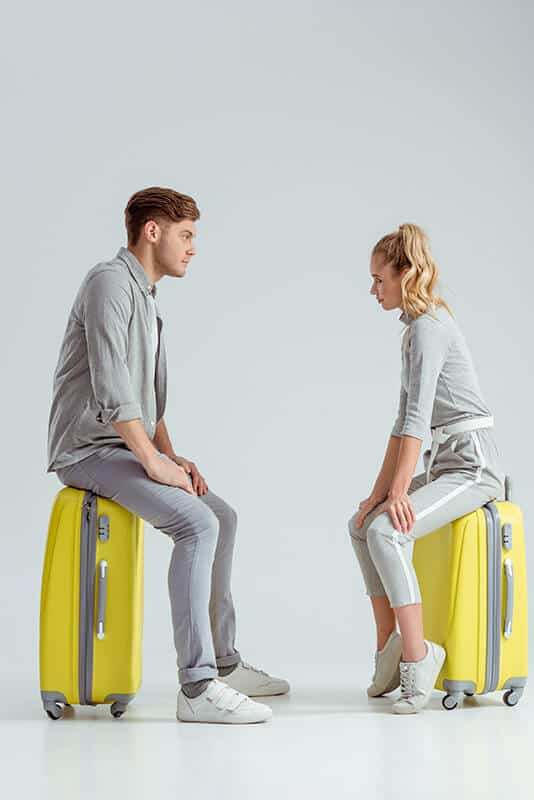 Couple sitting on suitcases