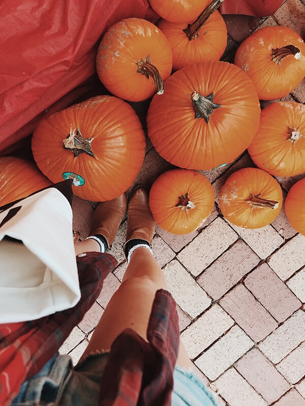 Girl next to a bunch of pumpkins