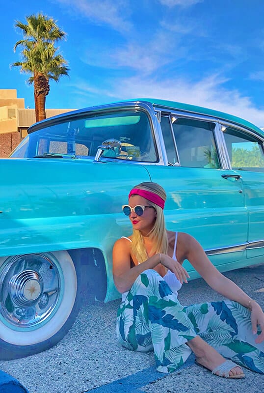 Girl sitting next to a blue cadillac