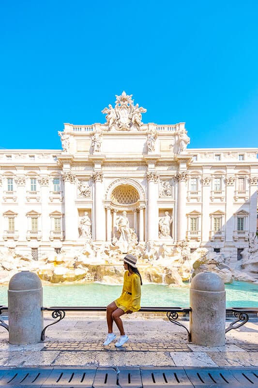 Woman sitting in front of the Trevi Fountain (Rome, Italy)